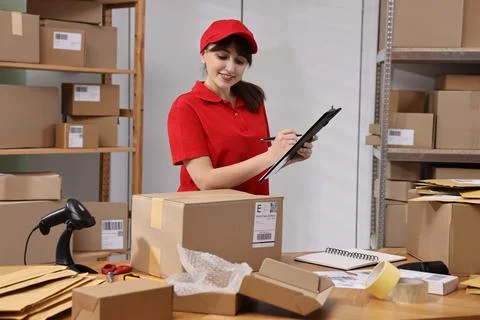 Parcel packing. Post office worker with clipboard at wooden table indoors Stock Photos