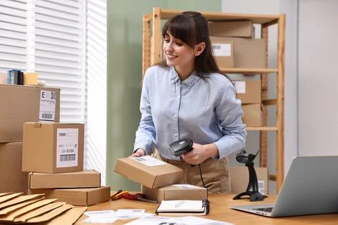Parcel packing. Post office worker with scanner reading barcode at wooden t.. Stock Photos