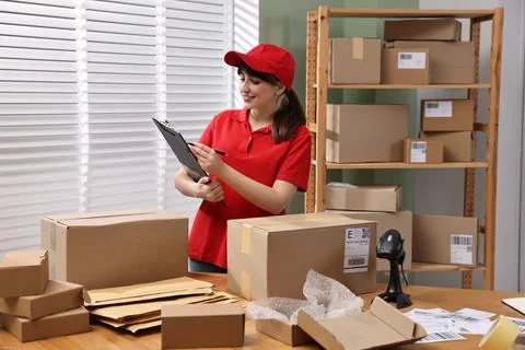 Parcel packing. Post office worker with clipboard at wooden table indoors Stock Photos