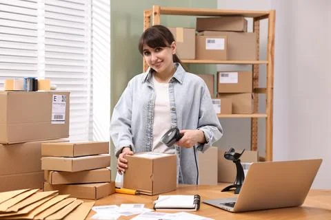 Parcel packing. Post office worker with scanner reading barcode at wooden t.. Stock Photos