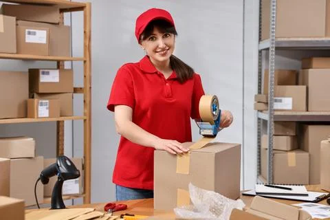 Parcel packing. Post office worker taping box at wooden table indoors Foto stock