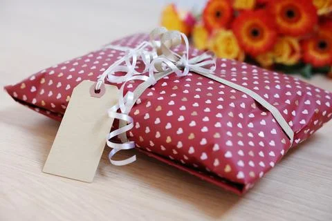 Parcel wrapped in heart patterned paper with cardboard tag on wooden table,.. Stock Photos