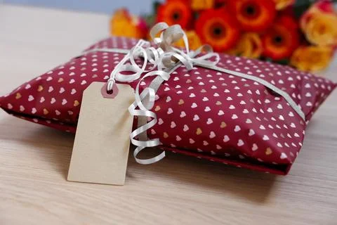 Parcel wrapped in heart patterned paper with cardboard tag on wooden table,.. Foto stock
