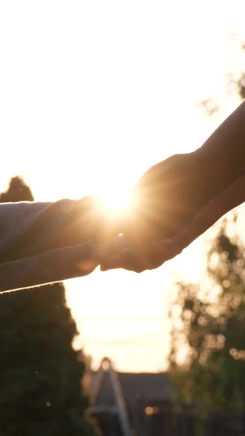Parent and child holding hands at sunset Stockbeeldmateriaal 316616536