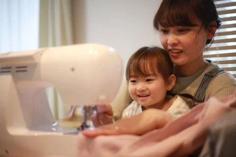 Parent and child using a sewing machine Foto stock