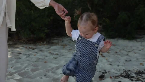 Parent and child walking on a sandy beach holding hands Stock Footage 345364555