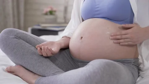 Parent is applying cream on her tummy Video stock 144550416