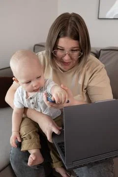 A parent balancing remote work responsibilities while caring for their baby 写真素材