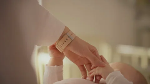 Parent gently holding babys hand while nurturing connection in a bright nurs Stock Footage 301406322