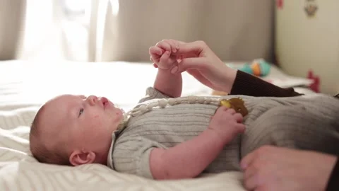 Parent gently holding newborn baby's hand while lying on bed Stock Footage 340629915