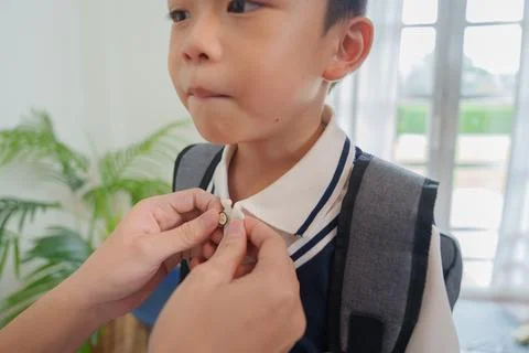 Parent helping child button uniform collar for back to school morning routine Stock Photos