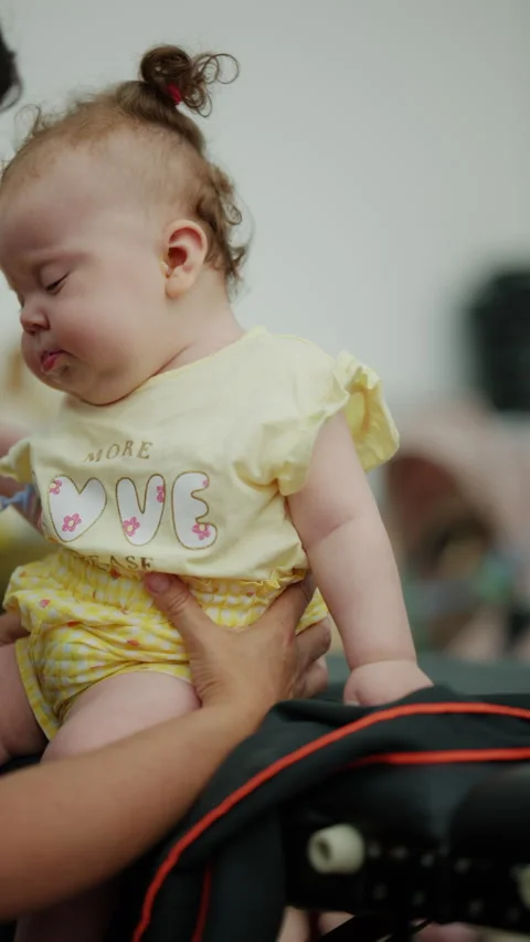 Parent holding a grumpy toddler a yellow shirt, the upset baby looking 動画素材 339810245