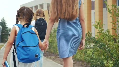 Parent leads to school child with backpack back view. kids go to school with Stock Footage 150340637