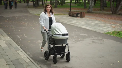 Parent navigating urban environment with baby stroller in hand. Mother Video stock 346400278