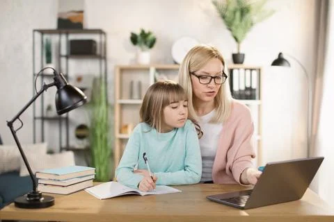 Parent or tutor helping child daughter with remote education Stock Photos