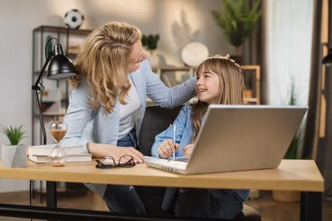Parent or tutor helping child daughter with remote education. Stock Photos