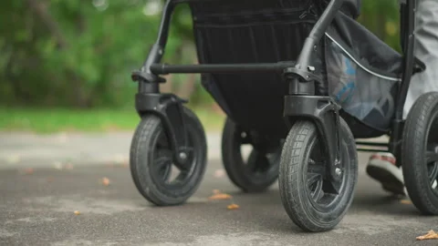 Parent pushing stroller on trail. Walking with baby in park during daytime Stockbeeldmateriaal 347318476