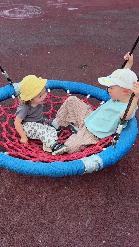 Parent pushing two children on basket swing at playground. Happy family Stock Footage 338055117