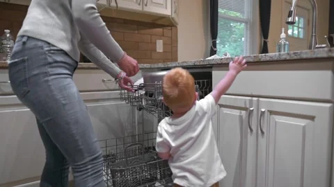 Parent supervises young child interacting with dishwasher, fostering curiosity Vidéo 290831639
