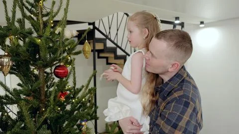Parent supporting young child while hanging festive ornaments, sharing warm Stock Photos