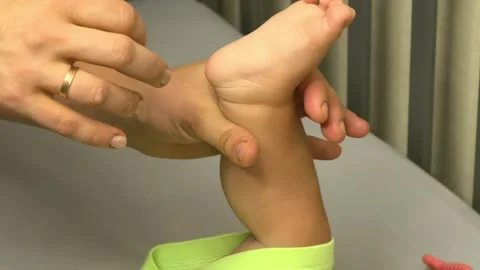 Parent tickles a baby's foot in close up at home, playful family interaction Stock Footage 346021122