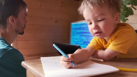 Parenthood multitasking, father work at home on computer and helps his son Video stock 130494948