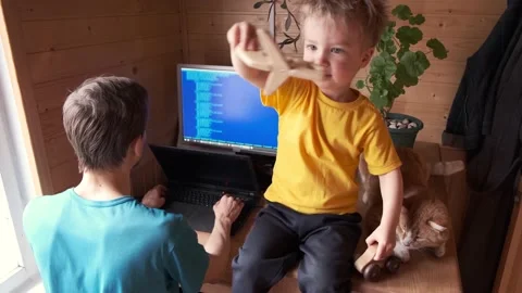 Parenthood multitasking, man working home, small child with cat sits and plays Видео 130494594