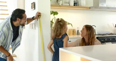 Parents and child measuring height father leaning with yellow tape on kitchen Stock Footage 342234867