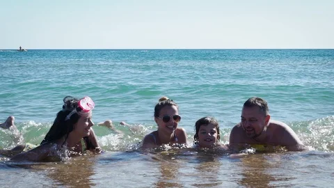 Parents and children lying in water at the sea shore.  Stock Footage 113687948