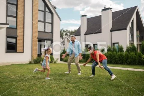 Parents and daughter playing hide and seek outside near house Stock Photos