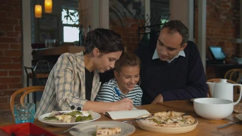 Parents and daughter write something together in notebook Stock Footage 120797953