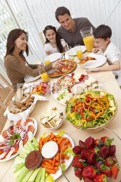 Parents children family eating pizza & salad at dining table Stock Photos