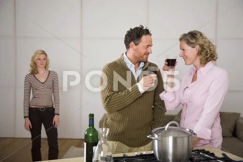 Parents clinking glasses, daughter standing in background Stock Photos