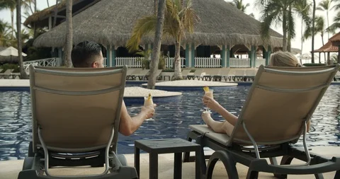 Parents with Drinks Poolside While Kids Jump Into Water, Tropical Resort Vidéo 112411670