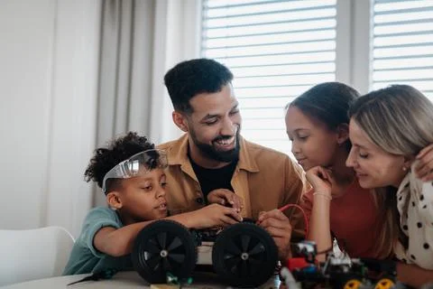 Parents encouraging children to explore robotics and technical skills. Stock Photos