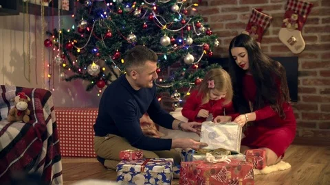 Parents help daughter open a gift on Christmas Stock Footage 82416136