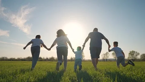 Parents hold toddler while swinging. Son runs beside group. Grass soft below Stock Footage 315340077
