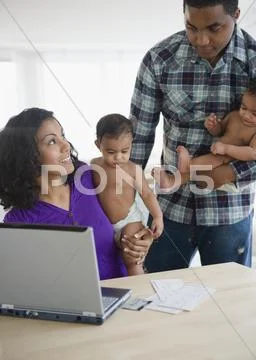 Parents Holding Babies And Paying Bills Online