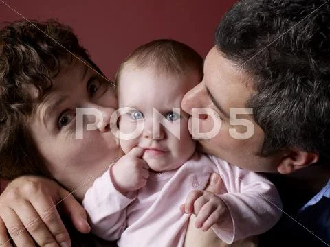 Parents Kissing Baby\'s Cheeks