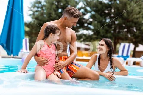 Parents laughing while swimming in pool with their lovely girl Stock Photos