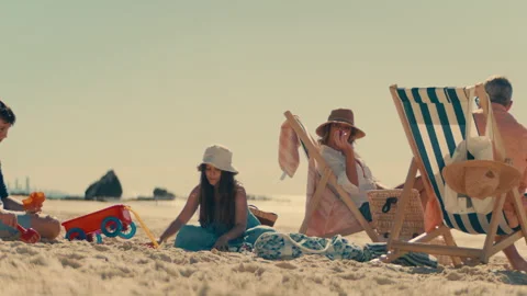 Parents lying on sun beds while children are playing in the sand Stock Footage 262408486