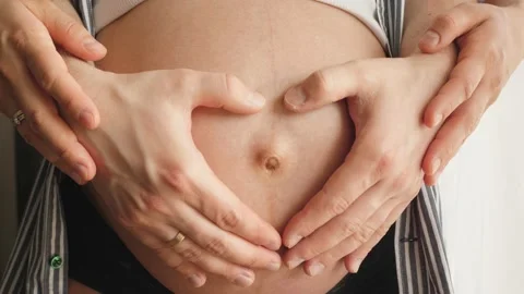 Parents make making a heart shape with their hands on pregnant belly 스톡 동영상 130795330