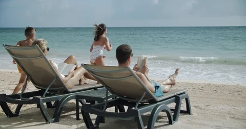 Parents Read Books on Beach, While Kids Play, Run to Ocean Stock Footage 112435308