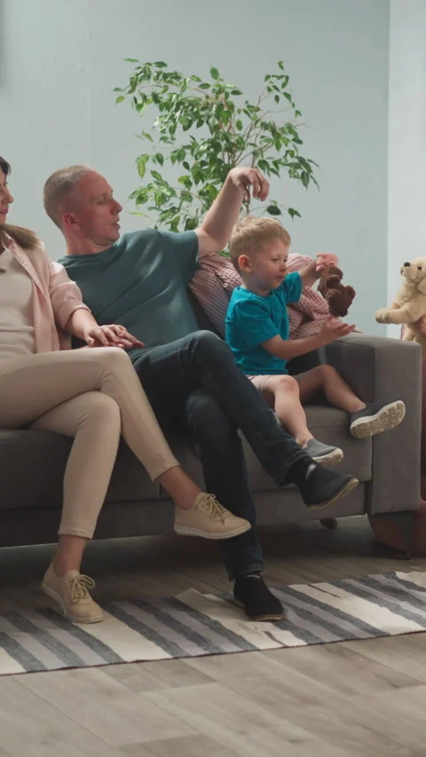 Parents rest on sofa while children play with toys at home Stock Footage 309882022