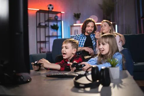 Parents resting on sofa while kids playing video games Stock Photos