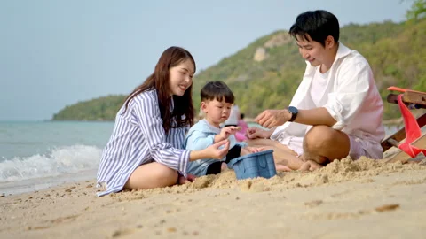 Parents sitting on beach chairs while watching their young child Stock Footage 338387736