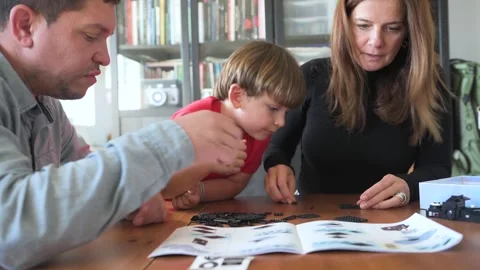 Parents with son sitting and picking up parts of puzzle Stock Footage 277224901