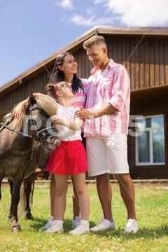 Parents standing near daughter touching nice brown horse Stock Photos