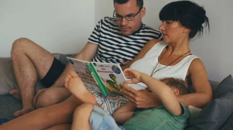 Parents Talking to Each Other While Small Son is Looking at Children's Book Video stock 63839609