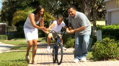Parents Teaching Son to Ride Bicycle Stock Footage